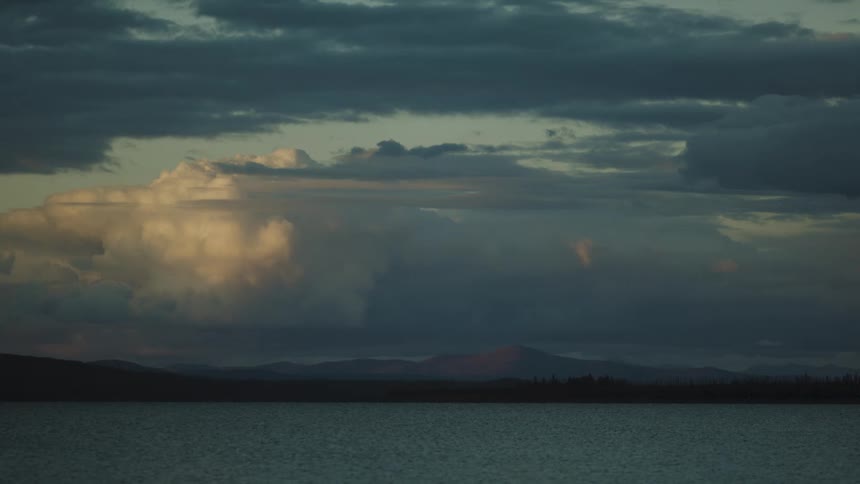 Thick clouds in the above a body of water outdoors at sunset