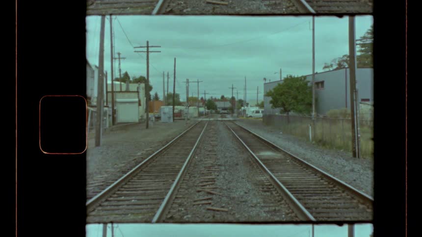 Two train tracks in an urban setting with several light poles