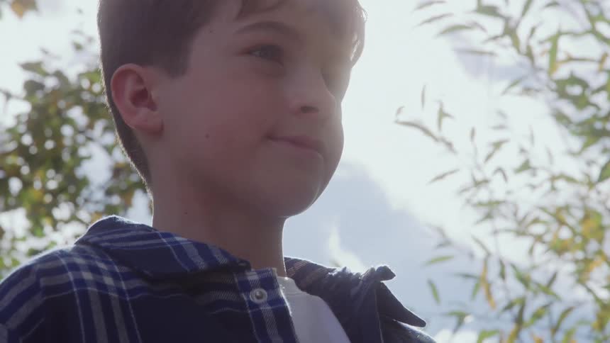 The boy is smiling outside on a sunny day