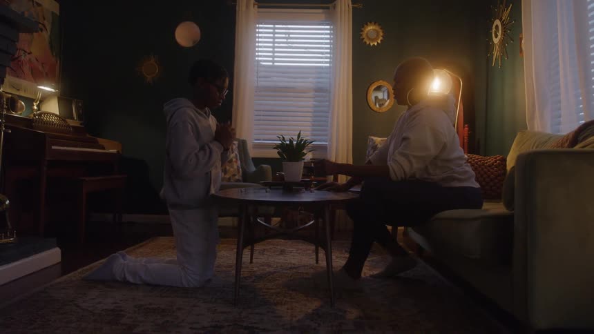 Mother and son play a dice game together in a warmly lit living room