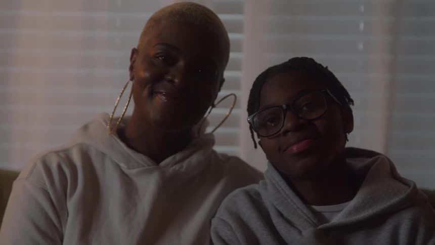 Mother and son sitting close together smiling warmly under soft light