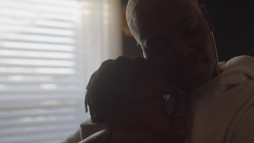 Mother holds her son in her arms bathed in the gentle light streaming through the window