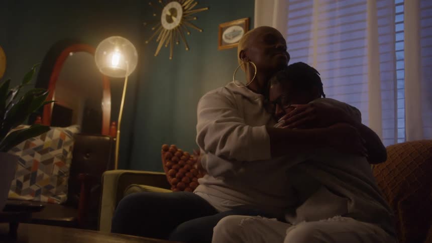 Mother and son share a comforting hug in a warmly lit living room