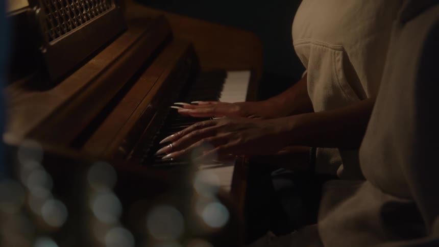 Hands gently play the piano keys in a cozy setting