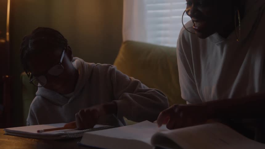 Mother helps her daughter work on her homework in their living room