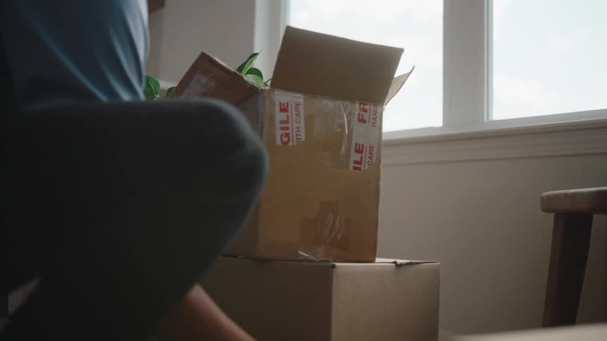 A man places down a full cardboard box on the floor