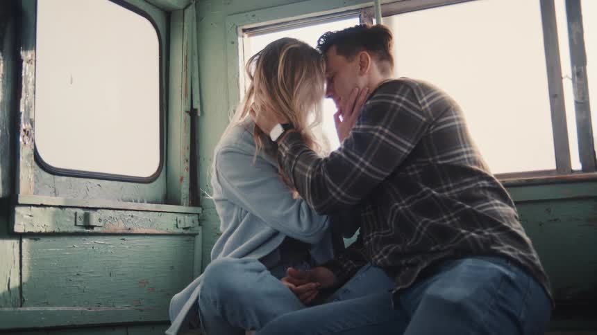 A young couple embraces closely while riding on a bus