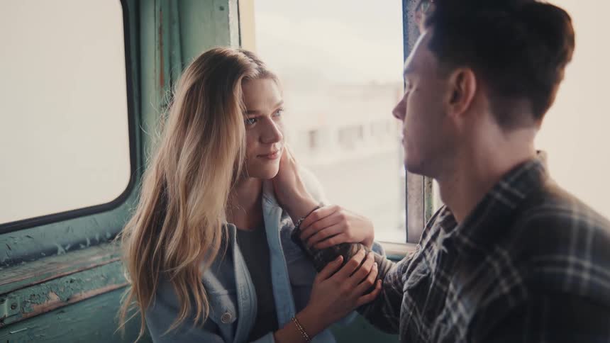 The man is touching a womans face by the window