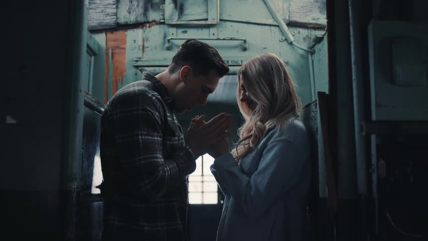 A young couple stands close as they rub each others hands to keep warm