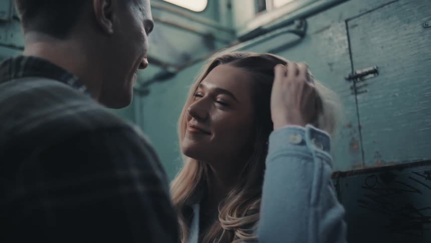 The man kisses the woman and brushes her hair back