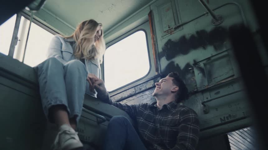 Couple sitting in a rustic space with large windows smiling and sharing a relaxed moment together