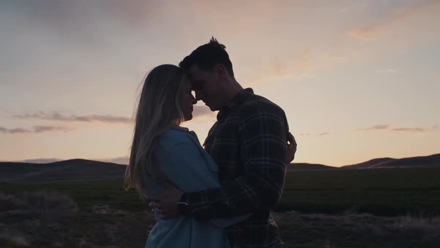 Couple embraces at sunset before the quiet landscape