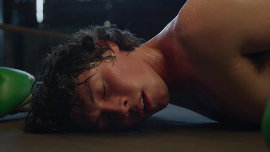 Man lying on the floor exhausted after a fall during boxing training