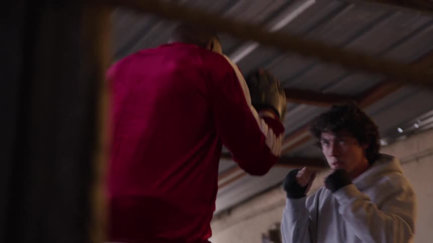 Boxer practices fast punches with the coach inside the ring