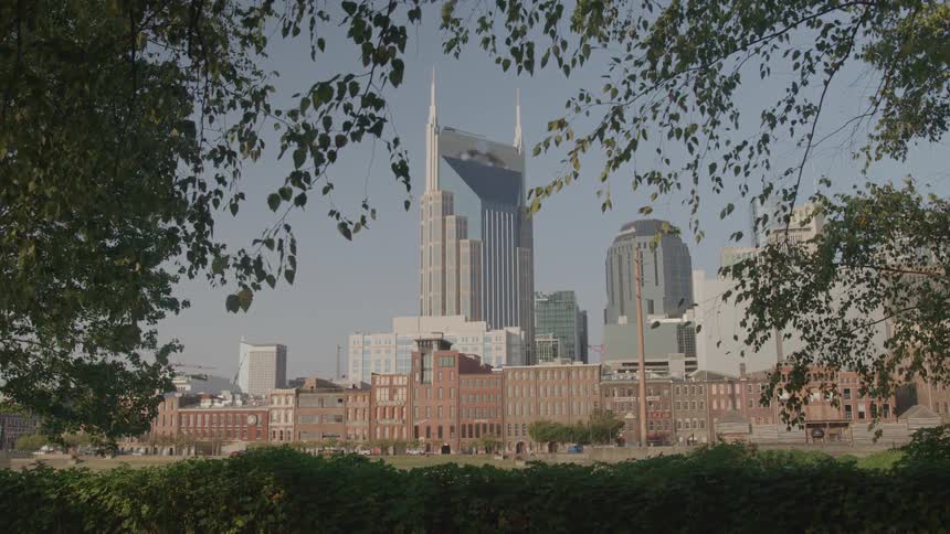 Cityscape with tall buildings in the background and trees framing the scene featuring modern architecture among historic structures