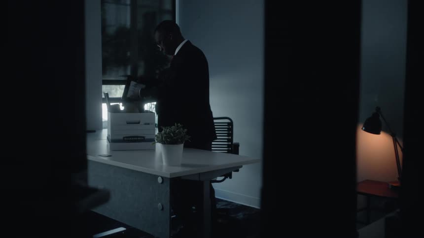 Male employee packs belongings into a box while leaving the company
