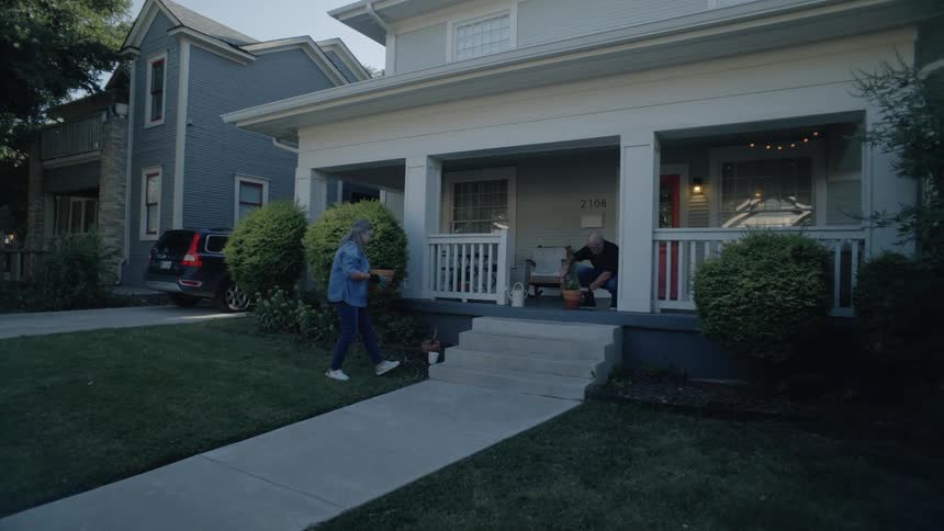 Couple gardens together on the porch of a suburban home