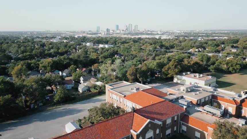 Aerial view of residential homes surrounded by trees with a distant city skyline