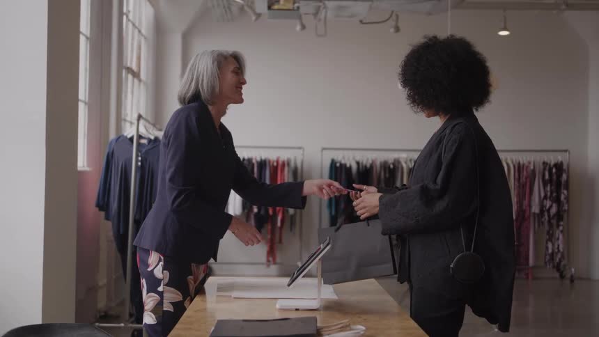 A happy woman customer pays with a credit card in a fashion showroom