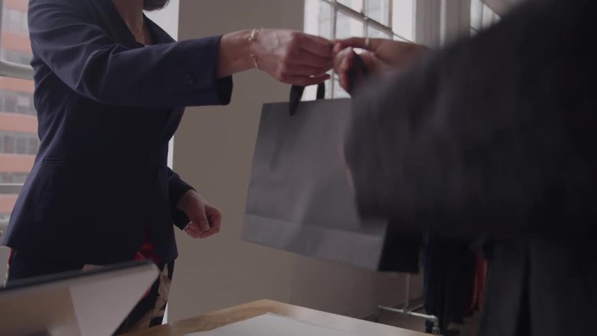 A woman handing over a bag to another woman in a modern boutique