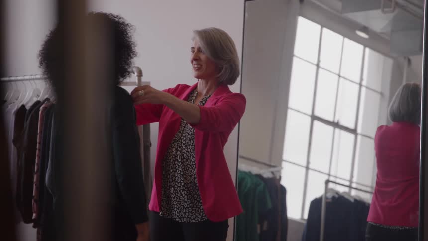 A designer measures a customer with a tape in a modern boutique