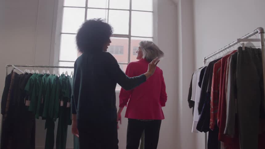 Two women looking at clothes in a fashion studio lit by natural light