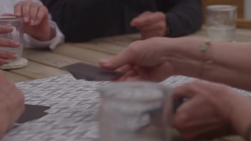 People sitting at a table holding playing cards