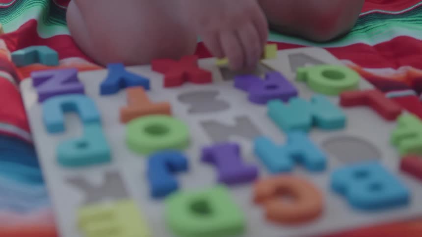 The video is a closeup shot of a young child with long curly hair looking down the child is wearing a bright lime green top outdoors in a sunny setting