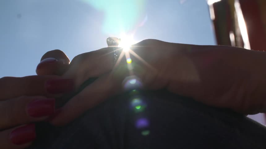 Persons hands under a bright sun