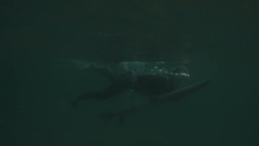 Surfer glides beneath the water amid the oceans darkness