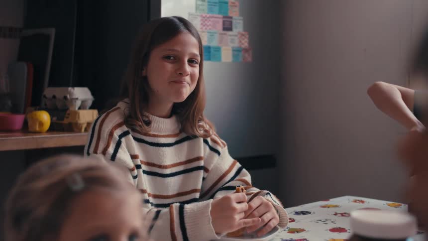 Girl smiles while eating at home with her family