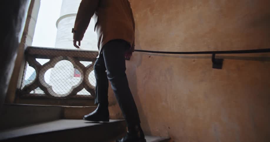 Person walks up a stone staircase in an old building lit by natural light