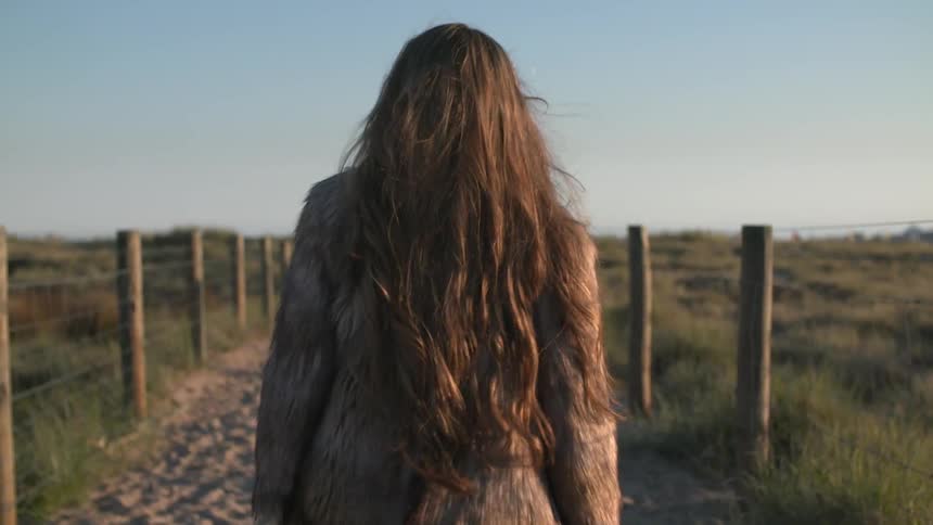 A woman tosses her hair as she follows a trail