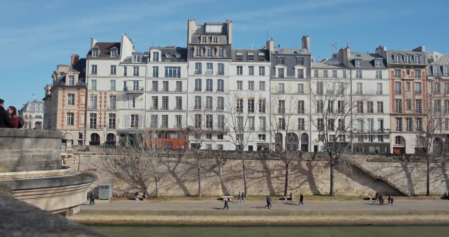 A group of people walks through a public park on a sunny day with highrise residential buildings framing the cityscape in the background