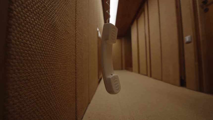 Close up of telephone hanging in a lit corridor with brown walls