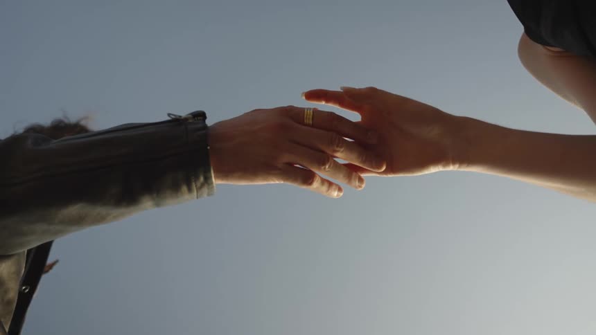 Hands touch gently under the clear sky