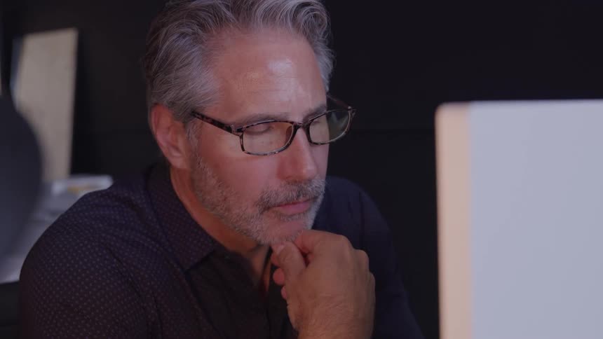 Close up of a middle aged man using a desktop computer in a room