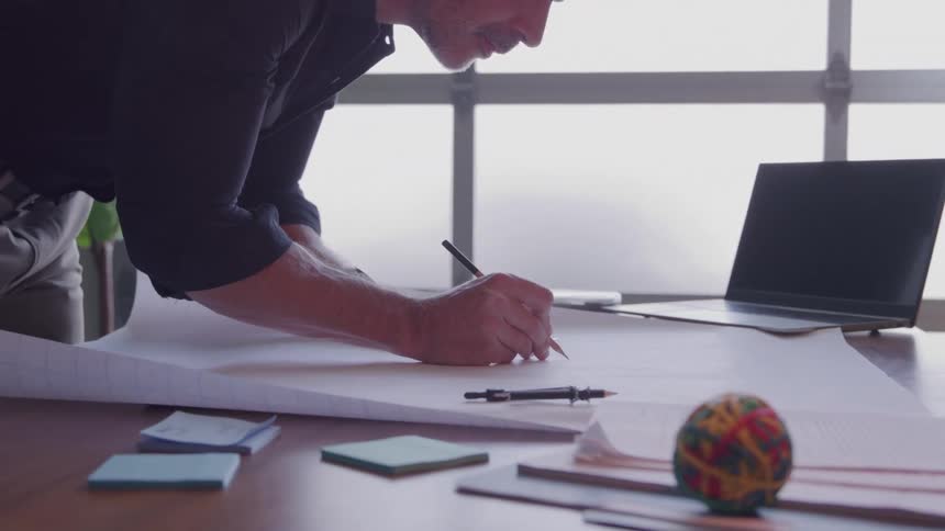 Man takes notes on a large project spread out on the work desk