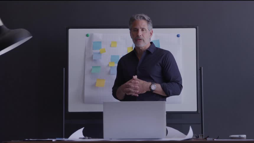 Man gives a presentation in front of a board with colorful notes