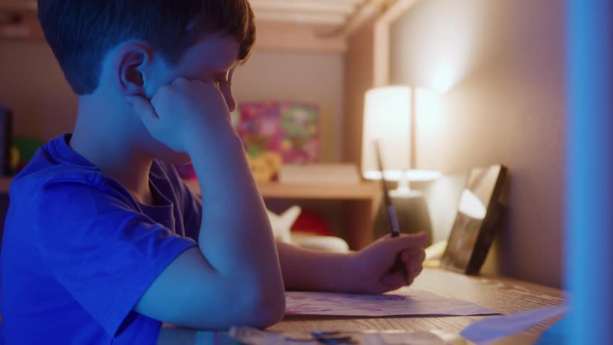 A child writes at a desk