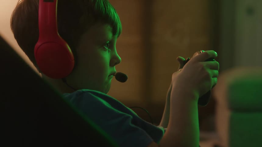 Boy focuses while playing video game with a controller in his hands