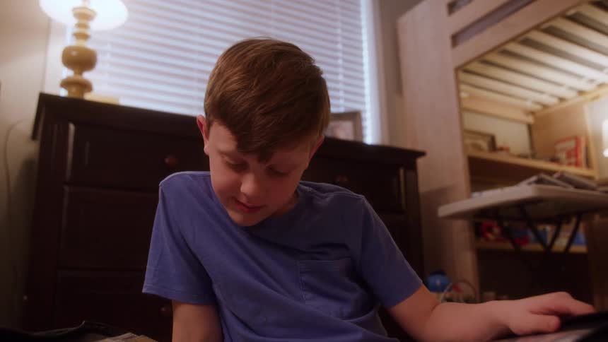 A boy sits on the floor looking at a binder