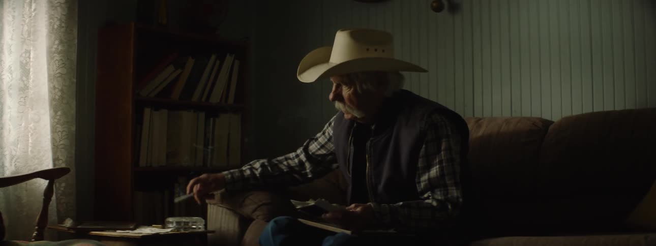 An older man takes a drag off a cigarette and puts it in an ashtray