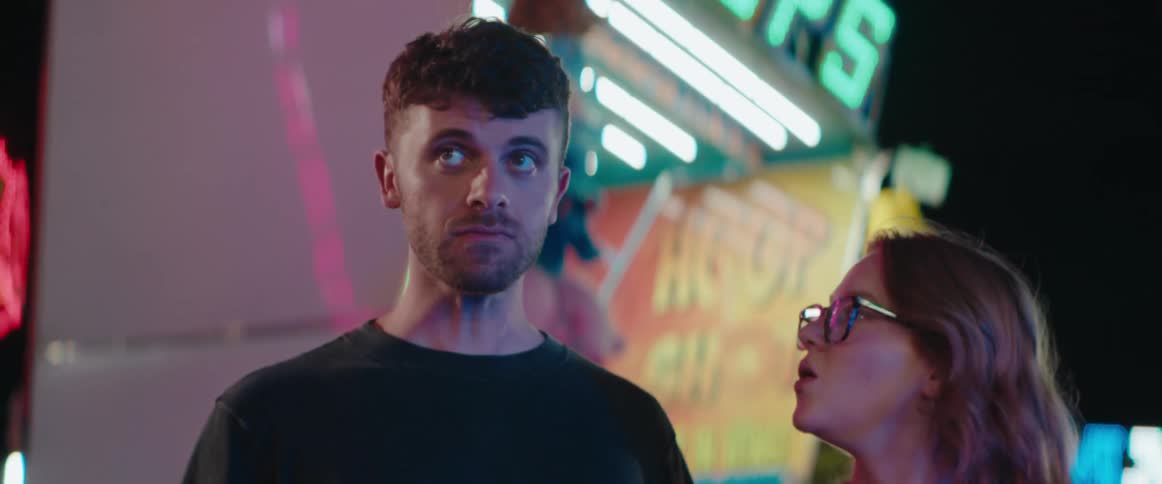 The man talks with a woman and points at the amusement park