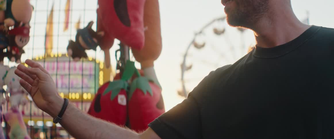 Man throws a dart next to his girlfriend at an amusement park