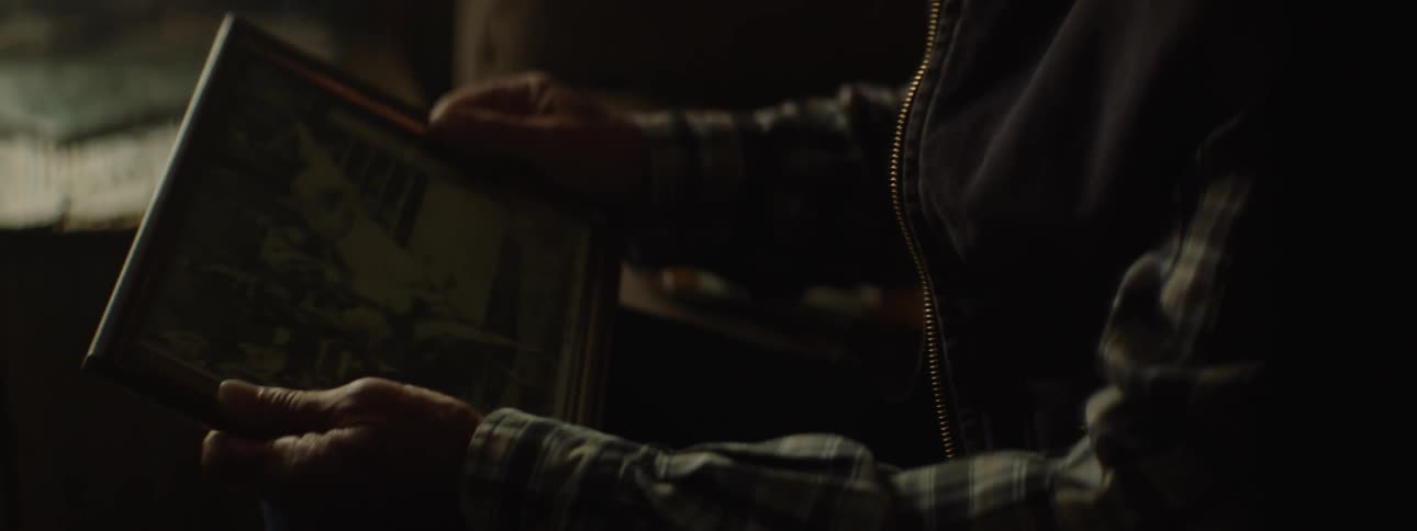 An elderly man in a cowboy hat lights a cigarette