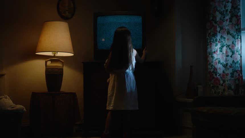 A girl is tapping the side of a television