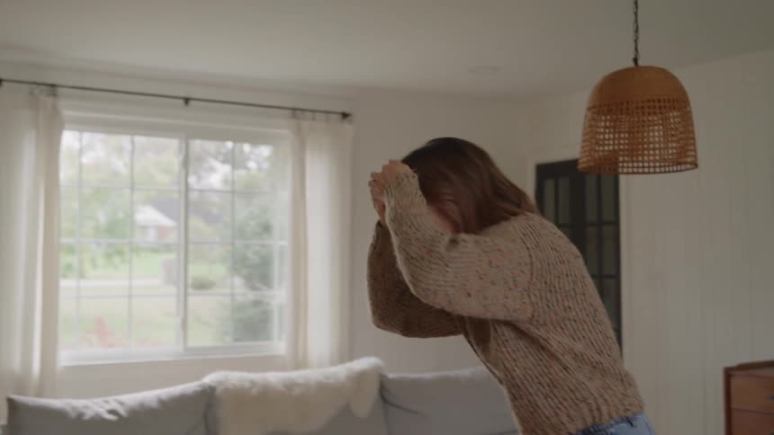 Couple smiles while dancing together in their living room on an autumn day