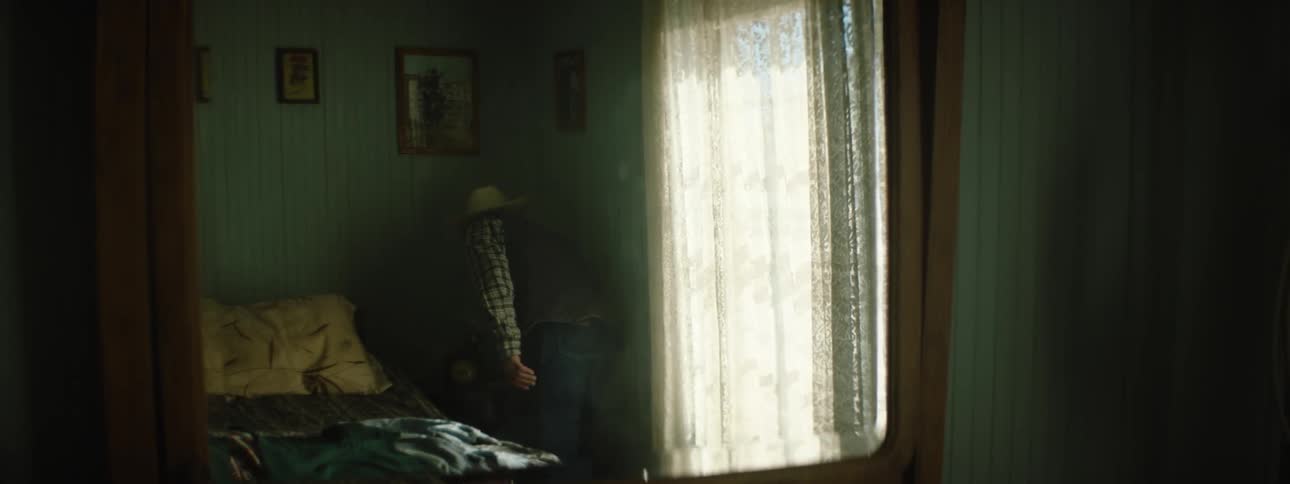 A man looks out a window before getting up