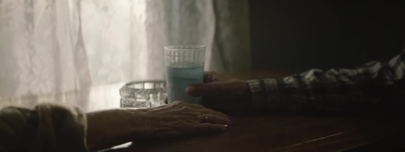 A man pulls a glass over the table